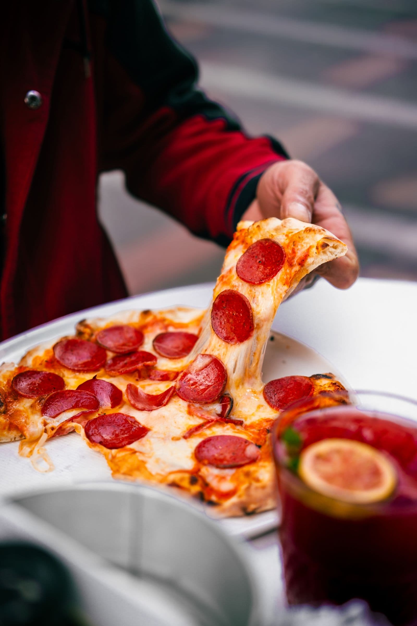 Fatia de pizza sendo levantada, com o queijo esticando