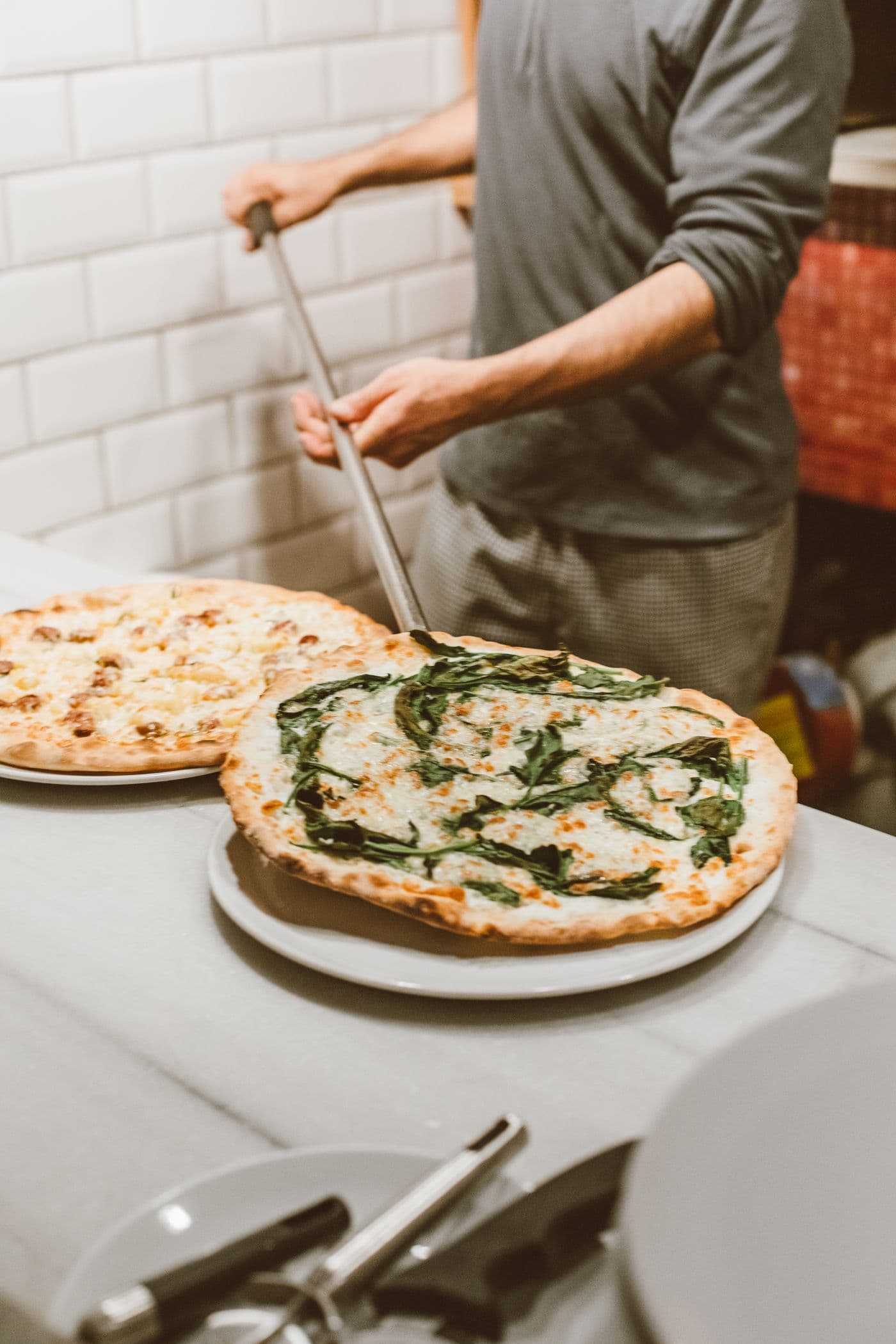 Pizzaiolo tirando pizzas do forno